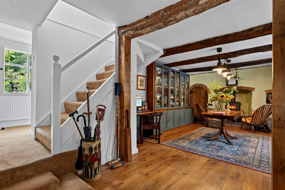 The library at Priors Court, Aylton, with glazed bookcases and a brick fireplace beyond