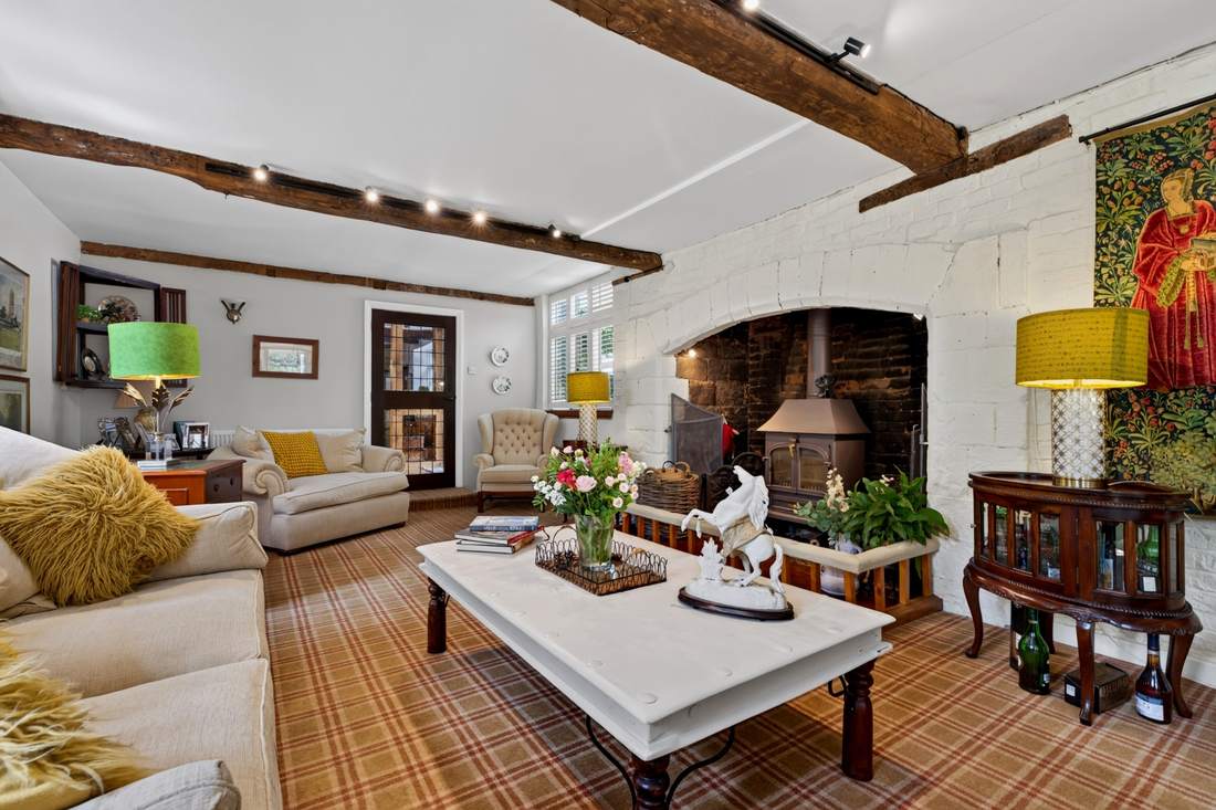 A reception room at Priors Court, Aylton, with a wood-burning stove and beamed ceiling