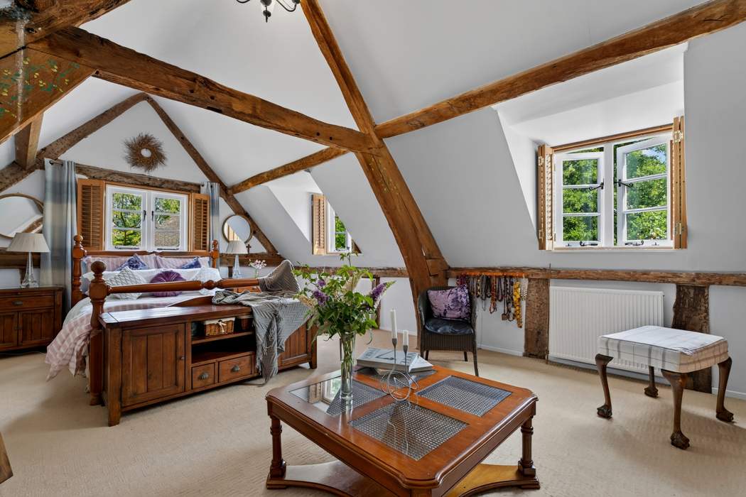 The principal bedroom at Priors Court, Aylton, with exposed roof timbers