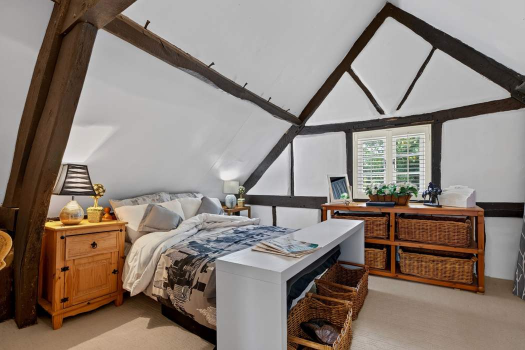 The top-floor bedroom at Priors Court, Aylton, set beneath the original roof timbers